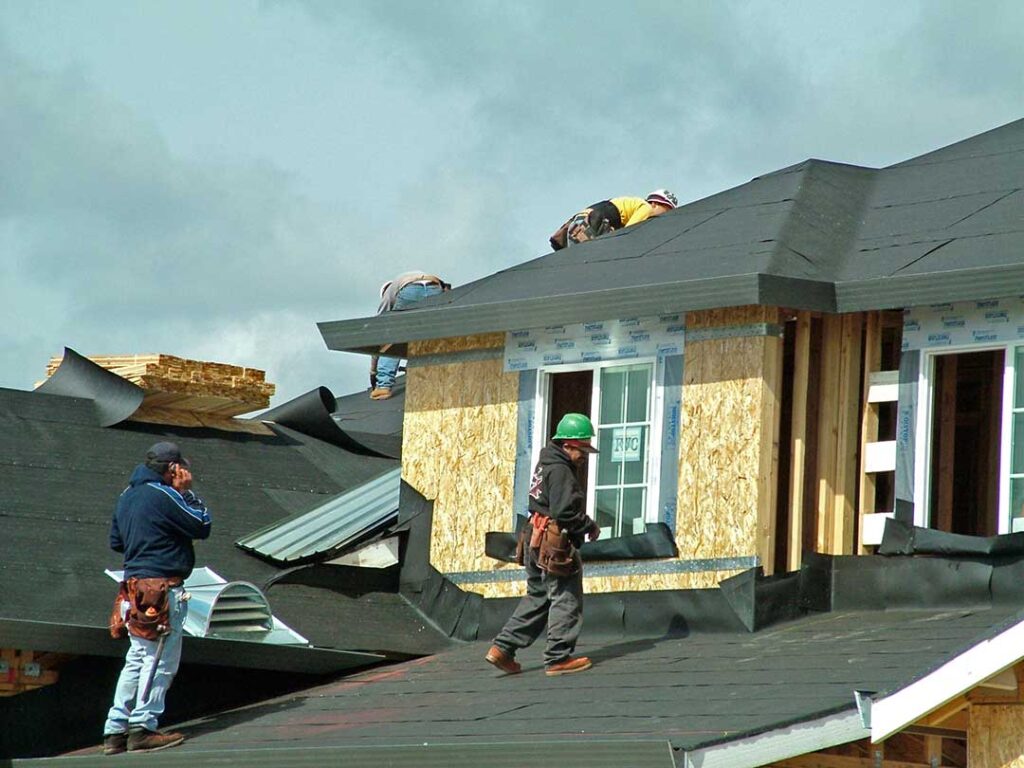 Homeowner reviews a roofing contract beside roof inspection photos and a calculator.
